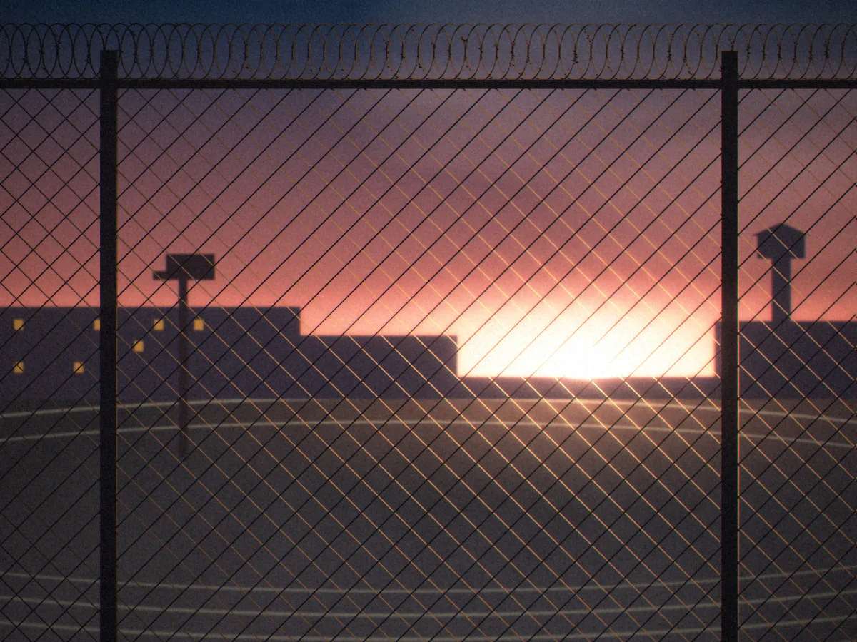 Convicted concept art: the exercise yard seen through a chain-link fence crowned with razor wire, with a painted running track, a basketball hoop and the cell blocks silhouetted against a pink and orange sunrise